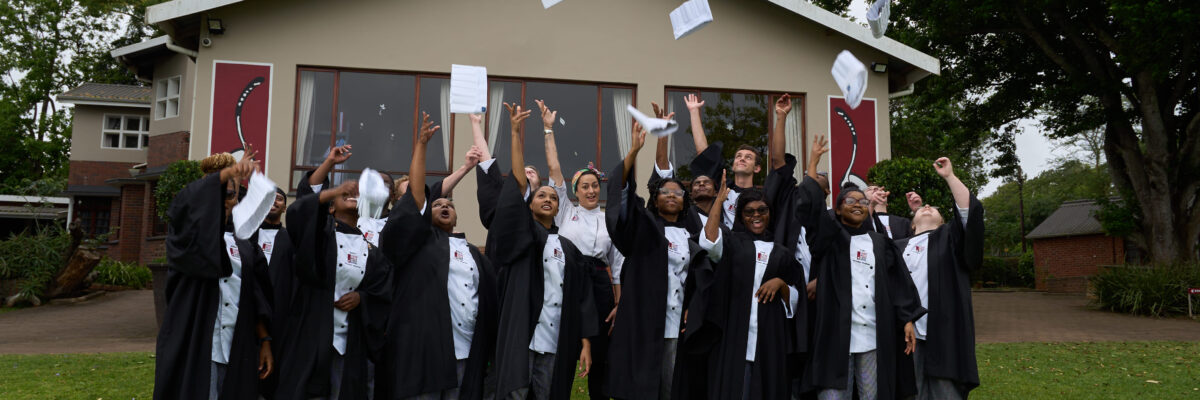 graduating chefs throwing chef hats in air as celebrating 100% pass rate at 1000 Hills Chef School